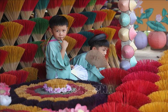 Young children in traditional Vietnamese clothes take photos with Thuy Xuan incense sticks. VNA Photo 
