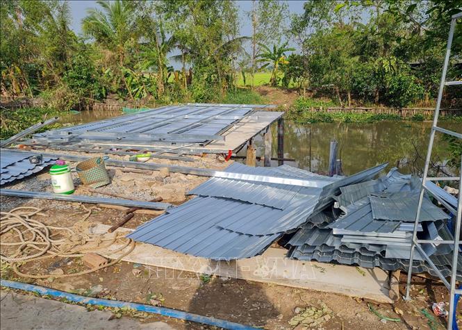 Một căn nhà bị sập do dông lốc ở huyện Cờ Đỏ đang được người dân sửa chữa lại vào chiều 16/6. Ảnh: TTXVN phát
