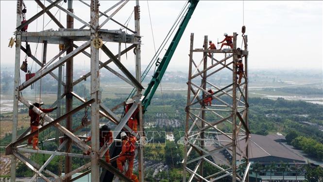 Công nhân Công ty Truyền tải điện 3 treo mình thi công lắp dựng cột thuộc địa phận tỉnh Thái Bình. Ảnh: Huy Hùng - TTXVN