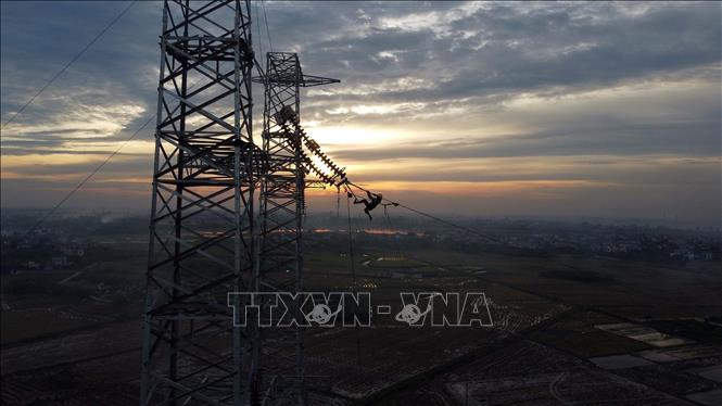 Công nhân nhà thầu Công ty CP Tư vấn đầu tư và Xây lắp Điện 5 (PCC5) thi công kéo dây trong ánh hoàng hôn tại vị trí cột 181 tuyến đường dây Nhà máy nhiệt điện Nam Định 1- Phố Nối trên địa bàn huyện Hưng Hà (Thái Bình). Ảnh: Huy Hùng - TTXVN