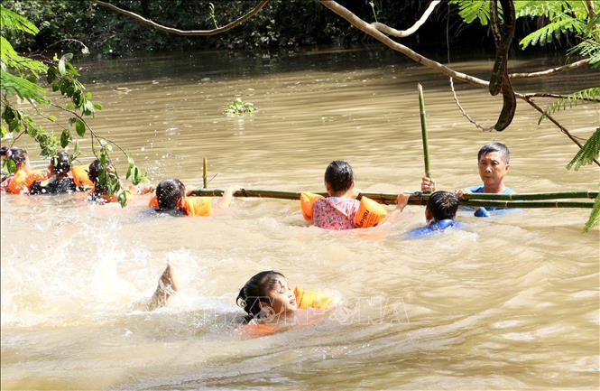 Giáo viên giám sát và hỗ trợ học sinh học bơi trên sông. Ảnh: Lê Thúy Hằng - TTXVN