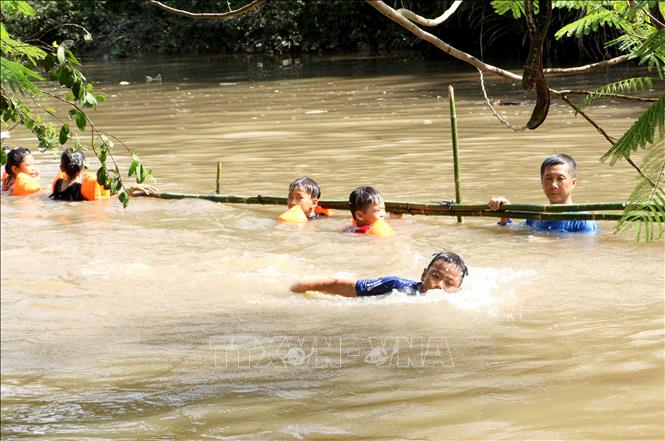 Giáo viên giám sát và hỗ trợ học sinh học bơi trên sông. Ảnh: Lê Thúy Hằng - TTXVN