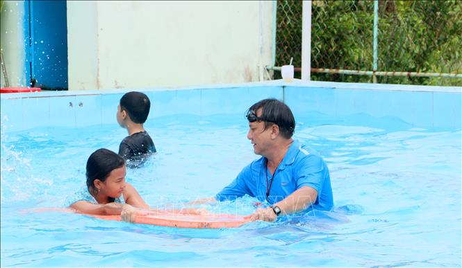 Giáo viên hỗ trợ thiếu nhi tập bơi. Ảnh: Lê Thúy Hằng - TTXVN 