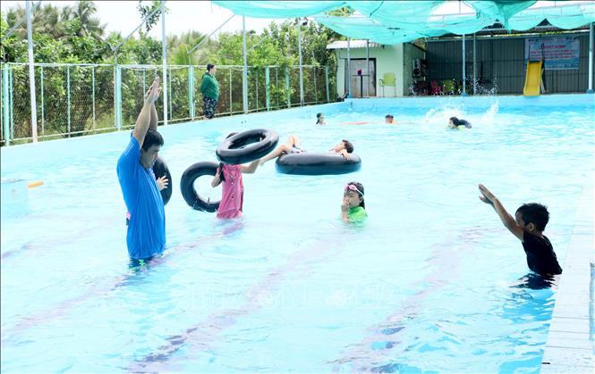 Giáo viên hướng dẫn kỹ thuật bơi cho thiếu nhi. Ảnh: Lê Thúy Hằng - TTXVN