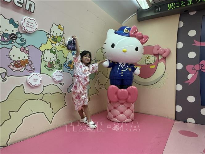 Một du khách nhí thích thú chụp ảnh cùng biểu tượng mèo Hello Kitty. Ảnh: Phạm Tuân - PV TTXVN tại Nhật Bản