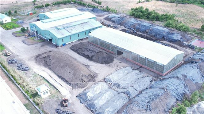 Bãi nguyên liệu của nhà máy phân hữu cơ vi sinh chỉ được che chắn sơ sài. Ảnh: Hoài Nam - TTXVN