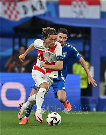 Tiền đạo Croatia Luka Modric (trái) đi bóng trong sự đeo bám của tuyển thủ Italy. Ảnh: THX/TTXVN