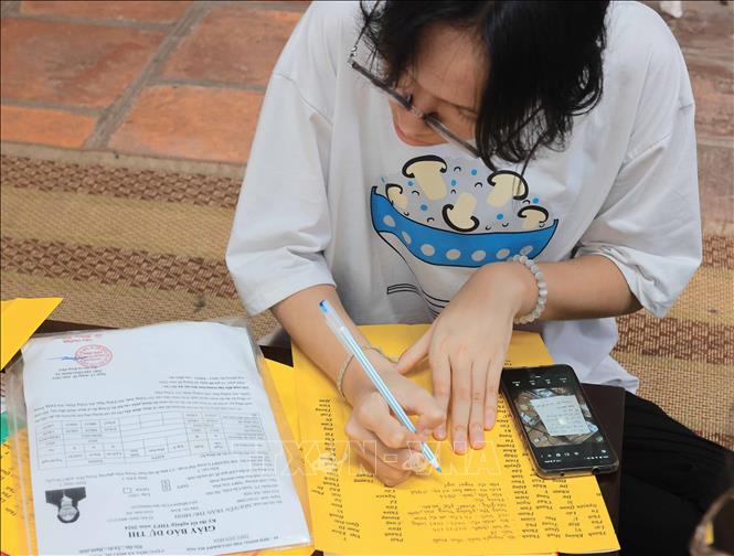Nhiều thí sinh viết sớ, cầu mong thi tốt. Ảnh: Hoàng Hiếu - TTXVN 