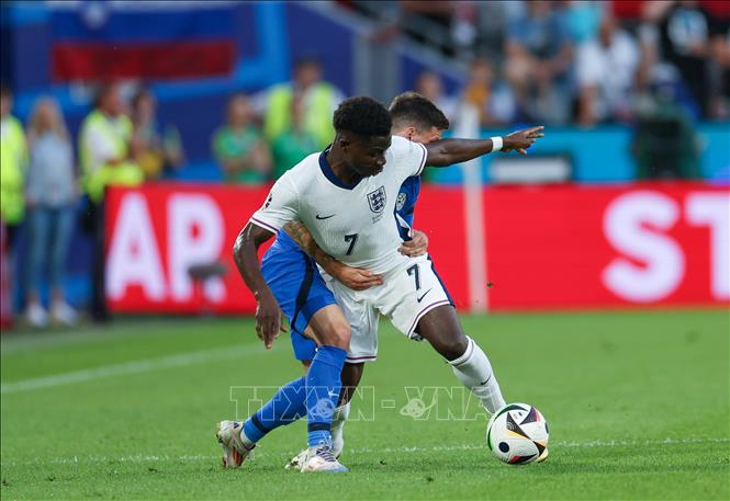 Bukayo Saka (số 7) của Anh tranh bóng với cầu thủ Slovenia. Ảnh: THX/TTXVN