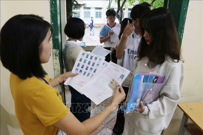 Giám thị kiểm tra giấy tờ của thí sinh trước khi vào phòng thi tại điểm thi Trường THPT thành phố Lai Châu. Ảnh: Nguyễn Oanh-TTXVN