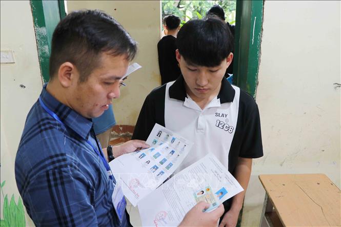 Giám thị kiểm tra giấy tờ của thí sinh trước khi vào phòng thi tại điểm thi Trường THPT thành phố Lai Châu. Ảnh: Nguyễn Oanh-TTXVN

