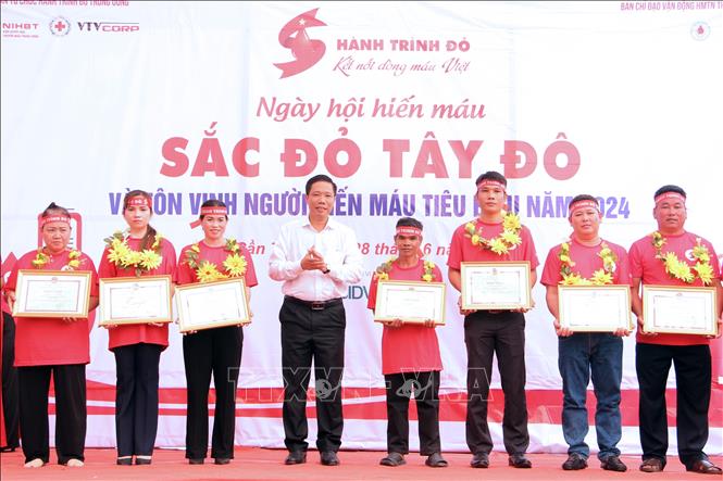 Ban tổ chức tôn vinh hộ gia đình và cá nhân có thành tích xuất sắc trong công tác hiến máu tình nguyện. Ảnh: Trung Kiên - TTXVN 