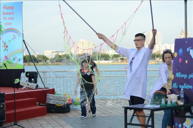 Giáo viên hướng dẫn các bạn nhỏ tham gia thí nghiệm khoa học tại chương trình. Ảnh: Văn Dũng-TTXVN