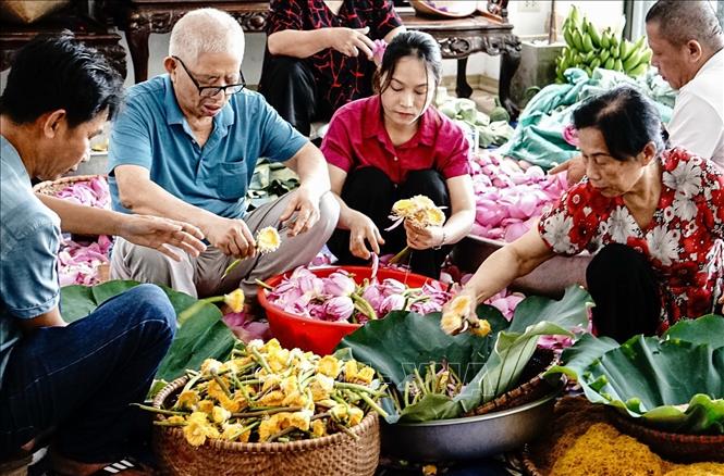 Nghệ nhân Ngô Văn Xiêm (78 tuổi) cùng các thành viên trong gia đình thực hiện các công đoạn ướp trà sen truyền thống. Ảnh: Khánh Hoà – TTXVN 