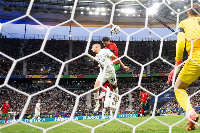 Pha tranh bóng bổng giữa Cristiano Ronaldo (phía trên) của Bồ Đào Nha và Vanja Drkusic của Slovenia. Ảnh: THX/TTXVN