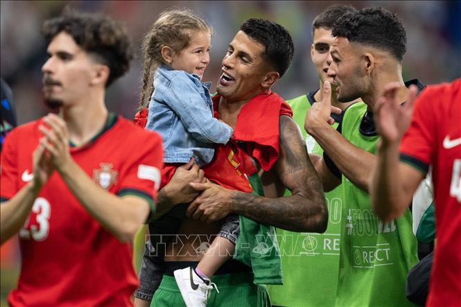 Cầu thủ Bồ Đào Nha Joao Cancelo (giữa) cùng con gái mừng chiến thắng sau khi tiếng còi kết thúc trận đấu vang lên. Ảnh: THX/TTXVN
