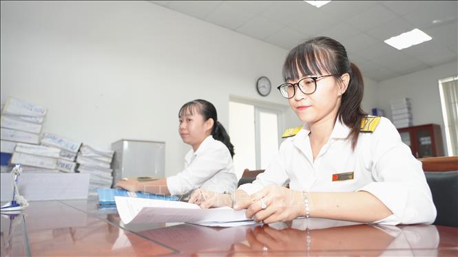Cán bộ Chi cục Thuế khu vực Hòa Thành - Dương Minh Châu, tỉnh Tây Ninh Quách Thị Hồng Loan (phải), thực hiện hướng dẫn doanh nghiệp, người nộp thuế thực hiện các thủ tục hành chính thuế. Ảnh: Minh Phú - TTXVN