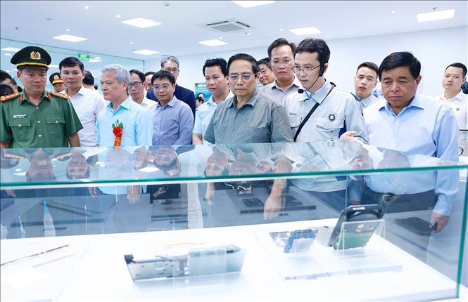 Thủ tướng Phạm Minh Chính xem sản phẩm bản mạch của Công ty TNHH Mektec Manufacturing chuyên sản xuất bản mạch. Ảnh: Dương Giang-TTXVN 
