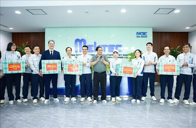 Thủ tướng Phạm Minh Chính tặng quà động viên công nhân của Công ty TNHH Mektec Manufacturing chuyên sản xuất bản mạch. Ảnh: Dương Giang-TTXVN 
