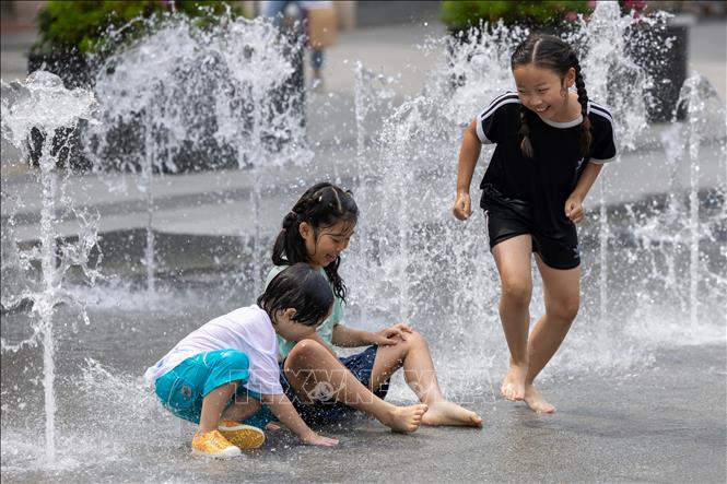 Các em nhỏ chơi đùa bên đài phun nước để tránh nóng tại Seoul, Hàn Quốc, ngày 21/6/2024. Ảnh: Yonhap/TTXVN