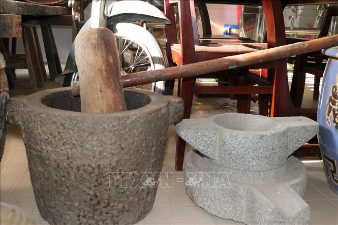Cối cùng chày giã gạo (trái) và cối xay bột (phải) được lưu trữ tại nhà ông Cao Tấn Hiệu. Ảnh: Hữu Chí - TTXVN