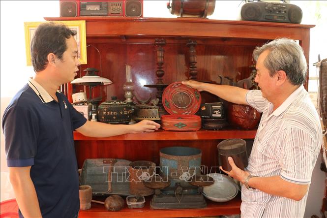 Ông Cao Tấn Hiệu (phải) giới thiệu giỏ đựng trầu do tổ tiên truyền lại. Ảnh: Hữu Chí - TTXVN