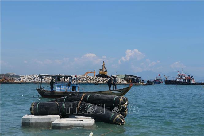 Tập trung đá hộc và hàng nghìn khối bê tông cách bờ biển từ 200- 250m để thi công đê ngầm. Ảnh: Đoàn Hữu Trung -TTXVN 