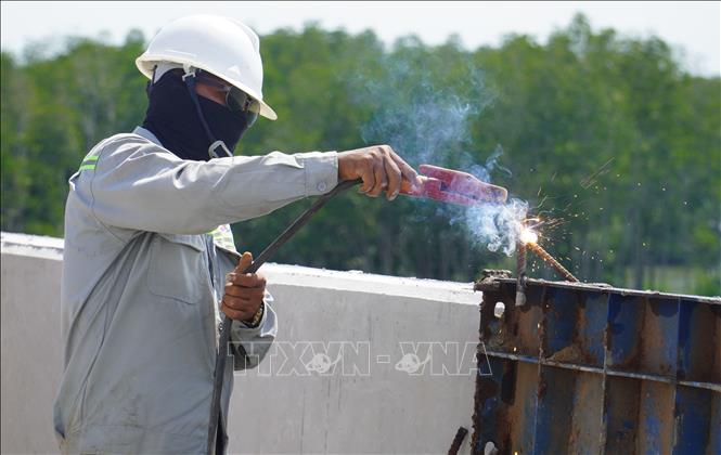 Công nhân hoàn thiện giải phân cách tại cao tốc Bến Lức - Long Thành. Ảnh: Công Phong - TTXVN
