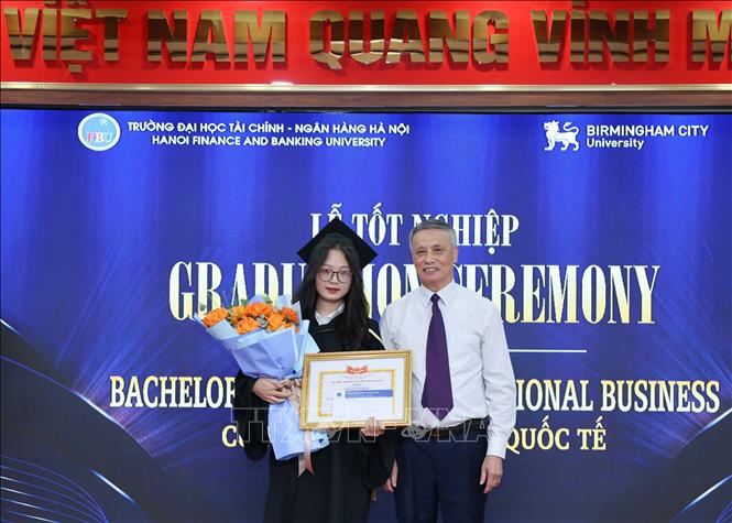 PGS.NGƯT Phạm Ngọc Ánh, Hiệu trưởng trường đại học Tài chính – Ngân hàng Hà Nội trao khen thưởng cho sinh viên Đào Hoài Phương, tốt nghiệp loại xuất sắc. Ảnh: Thanh Tùng - TTXVN