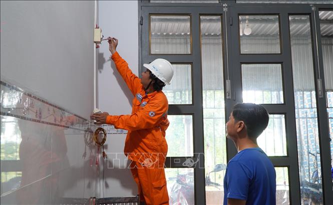 Nhân viên điện lực tỉnh Đồng Tháp hỗ trợ người dân lắp công tơ chống giật để đảm bảo an toàn trong quá trình sử dụng điện. Ảnh: Nhựt An - TTXVN