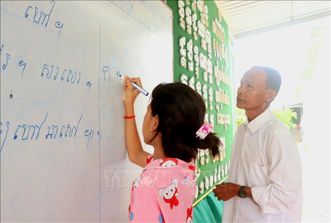 Ông Thạch Diễm, dạy đọc chữ Khmer cho các học sinh tại lớp dạy chữ Khmer ấp Thới Trường 1, xã Thới Xuân. Ảnh: Thu Hiền - TTXVN