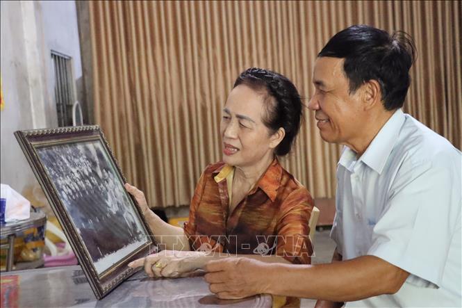 Vợ chồng nghệ nhân Phạm Thế Nhuần và nghệ nhân Vũ Thị Thanh Minh bên bức ảnh Đoàn văn công Nhân dân Nghệ Tĩnh lưu diễn phục vụ chiến trường. Ảnh: Hoàng Ngà - TTXVN