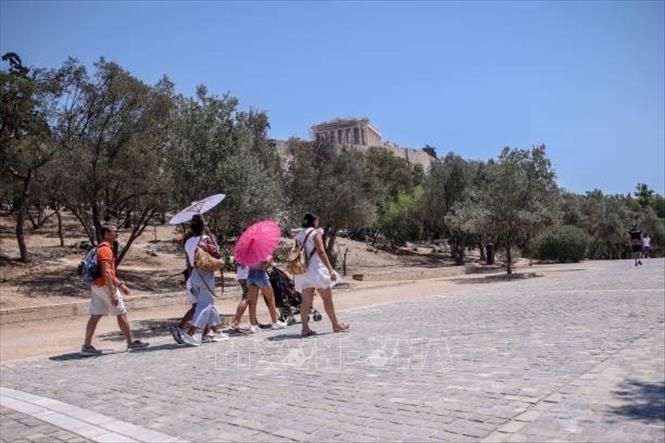 Du khách che ô tránh nắng nóng khi tham quan thành cổ Acropolis ở Athens, Hy Lạp, ngày 12/7/2024. Ảnh: Getty Images/ TTXVN