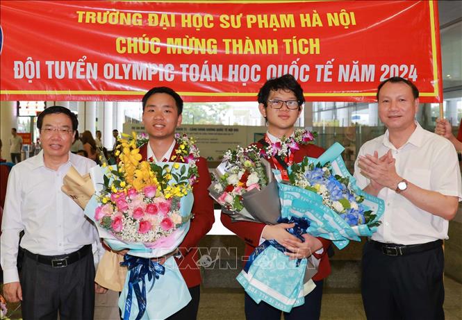 PGS.TS Nguyễn Đức Sơn, Hiệu trưởng trường đại học Sư Phạm Hà Nội) đón, tặng hoa chúc mừng hai học sinh. Ảnh: Thanh Tùng - TTXVN