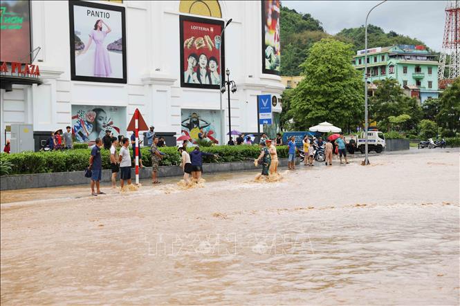Lực lượng Cảnh sát giao thông, Công an thành phố Sơn La, giúp người dân đi qua đoạn đường bị ngập nước khu vực đường Trường Chinh, phường Quyết Thắng. Ảnh: Nguyễn Cường - TTXVN