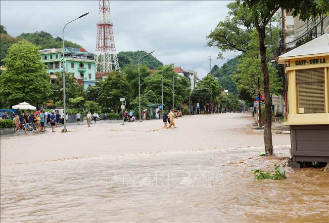 Lực lượng Cảnh sát giao thông, Công an thành phố Sơn La, giúp người dân đi qua đoạn đường bị ngập nước ở khu vực đường Trường Chinh, phường Quyết Thắng. Ảnh: Nguyễn Cường - TTXVN