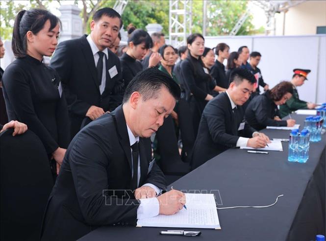 Bí thư Huyện ủy Đông Anh (trái) Nguyễn Trung Kiên ghi sổ tang. Ảnh: TTXVN