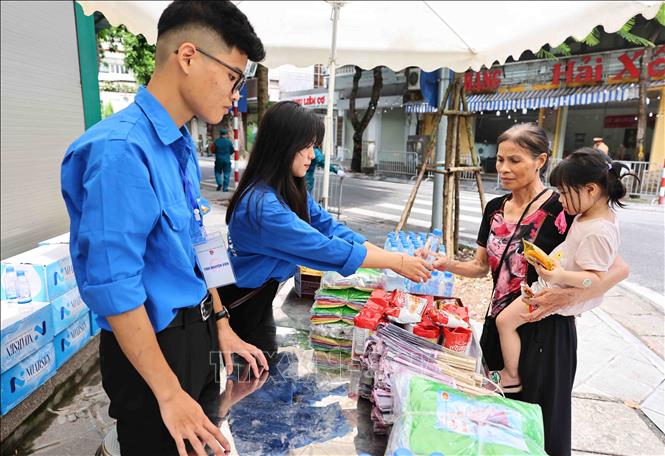 Các tình nguyện viên Thủ đô cung cấp nước uống, đồ ăn nhẹ, quạt giấy cho người dân. Ảnh: Minh Đức – TTXVN