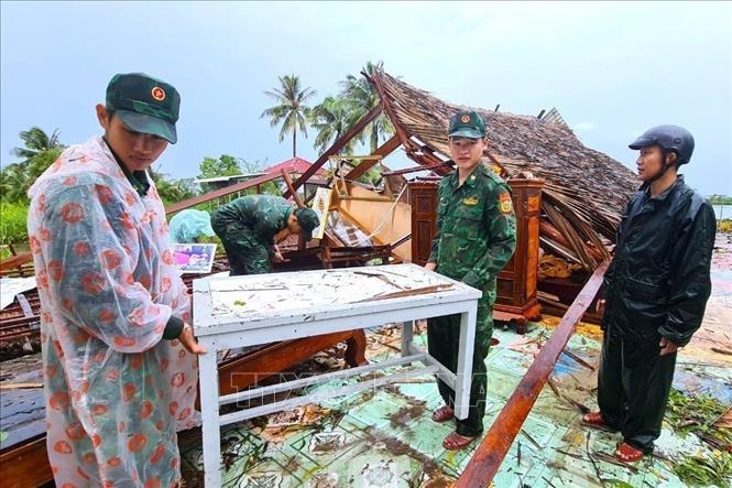 Cán bộ, chiến sĩ đồn Biên phòng Khánh Tiến, huyện U Minh, giúp người dân khắc phục hậu quả sau thiên tai. Ảnh: TTXVN phát