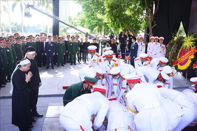 Honour guards slowly lower the coffin into the grave. VNA Photo