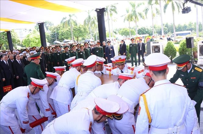Honour guards slowly lower the coffin into the grave. VNA Photo