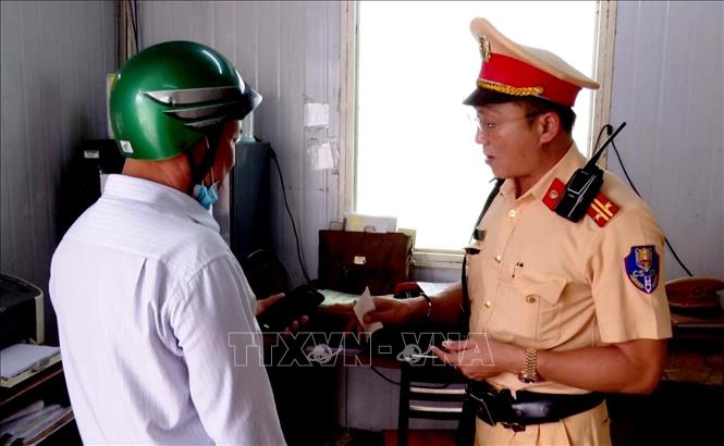Cán bộ, chiến sĩ Trạm CSGT Tuy Phước, Phòng CSGT Công an tỉnh Bình Định hướng dẫn người dân tích hợp giấy phép lái xe, giấy tờ xe trên ứng dụng VneID. Ảnh: Lê Phước Ngọc - TTXVN