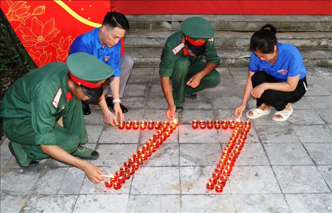 Đoàn viên thanh niên thắp nến hình số 77, tương ứng với 77 năm ngày Thương binh liệt sĩ tối 26/7/2024. Ảnh: Phan Quân - TTXVN