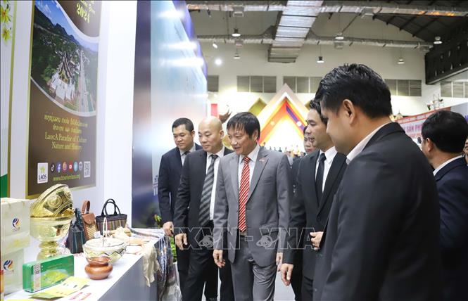 Đại sứ Việt Nam tại Lào Nguyễn Bá Hùng và các đại biểu tham quan gian hàng của Lào. Ảnh: Xuân Tú - PV TTXVN tại Lào