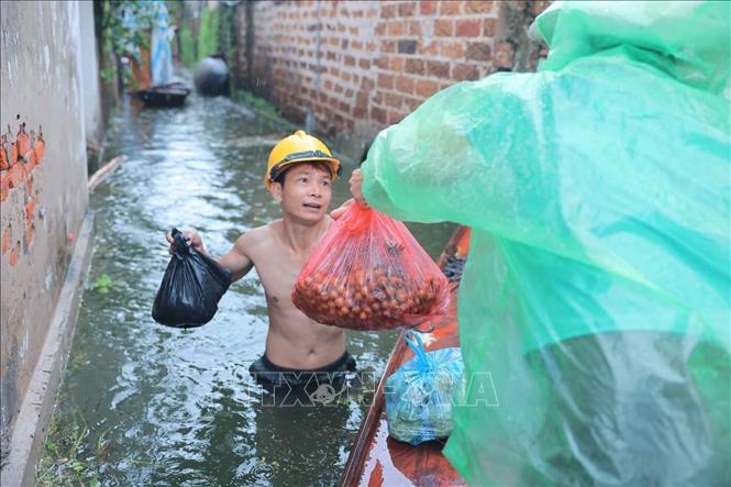 Người dân làng Hạnh Bồ nhận đồ tiếp tế do bị nước cô lập. Ảnh: Hoàng Hiếu - TTXVN