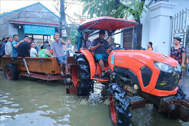 Anh Bùi Ngọc Bình, Trưởng thôn Nam Hài dùng phương tiện cá nhân giúp bà con chạy ngập, chuyển đồ đạc cần thiết, di chuyển trong thôn ra ngoài và ngược lại. Ảnh: Hoàng Hiếu - TTXVN