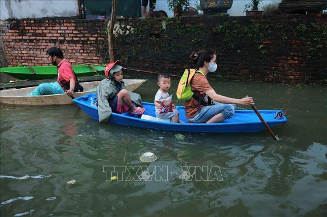 Đường làng thôn Tiên Tiến, xã Tân Tiến ngập sâu, người dân phải di chuyển bằng thuyền vào thôn. Ảnh: Hoàng Hiếu - TTXVN