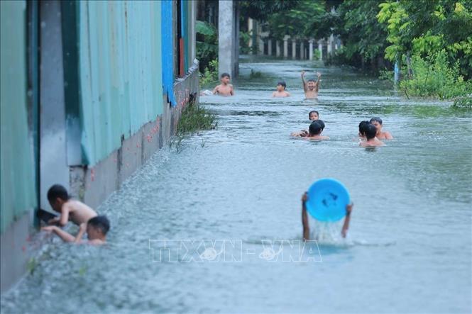 Đường làng thôn Tiên Tiến, xã Tân Tiến ngập sâu thành nơi trẻ em bơi lội. Ảnh: Hoàng Hiếu - TTXVN