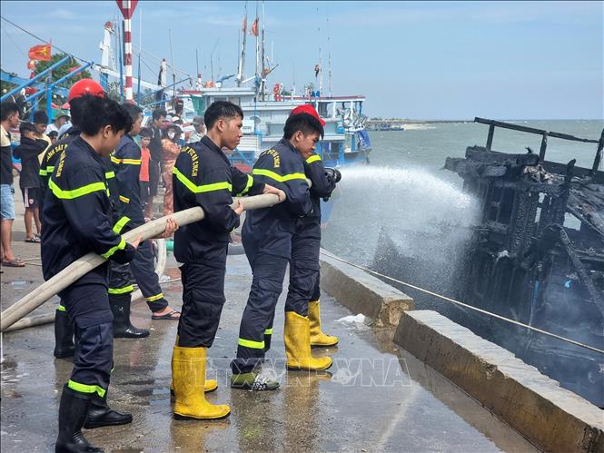 Cảnh sát phòng cháy, chữa cháy và cứu nạn, cứu hộ Công an tỉnh Ninh Thuận phun nước dập tắt đám cháy trên tàu cá. Ảnh: Nguyễn Thành - TTXVN