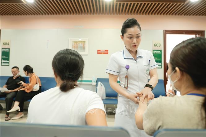 Nhân viên y tế hỗ trợ bệnh nhân đến khám bệnh. Ảnh: Minh Quyết - TTXVN